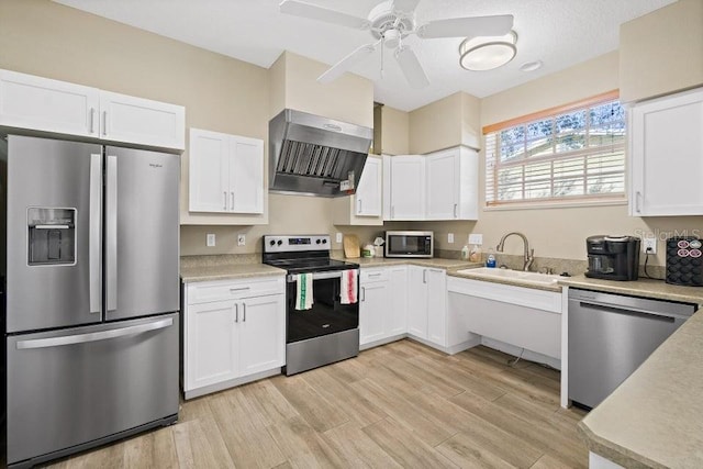 kitchen featuring wall chimney exhaust hood, white cabinetry, sink, and appliances with stainless steel finishes