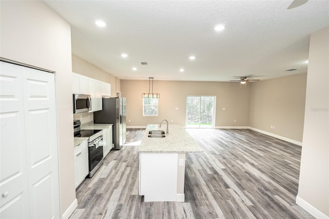 kitchen featuring a center island with sink, sink, light hardwood / wood-style floors, white cabinetry, and stainless steel appliances