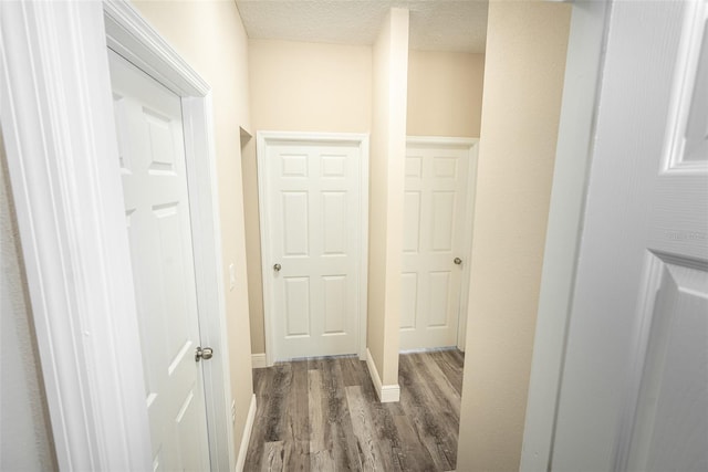 hall featuring dark wood-type flooring and a textured ceiling