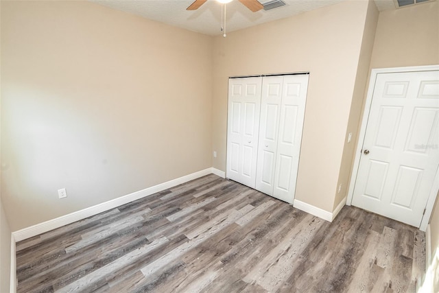 unfurnished bedroom with a closet, ceiling fan, hardwood / wood-style floors, and a textured ceiling