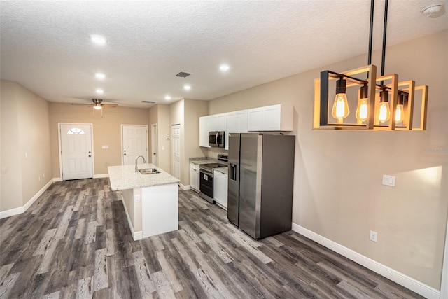 kitchen featuring a kitchen island with sink, white cabinets, dark hardwood / wood-style floors, appliances with stainless steel finishes, and decorative light fixtures