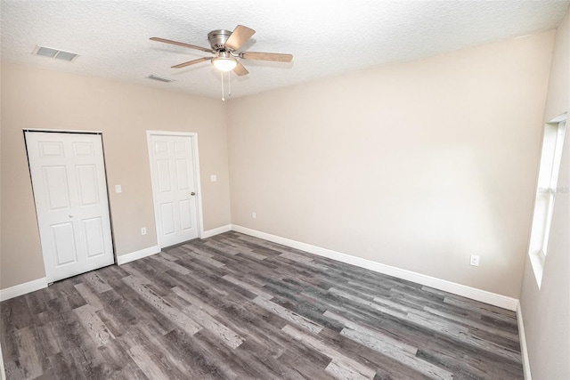 unfurnished bedroom featuring ceiling fan, dark wood-type flooring, and a textured ceiling