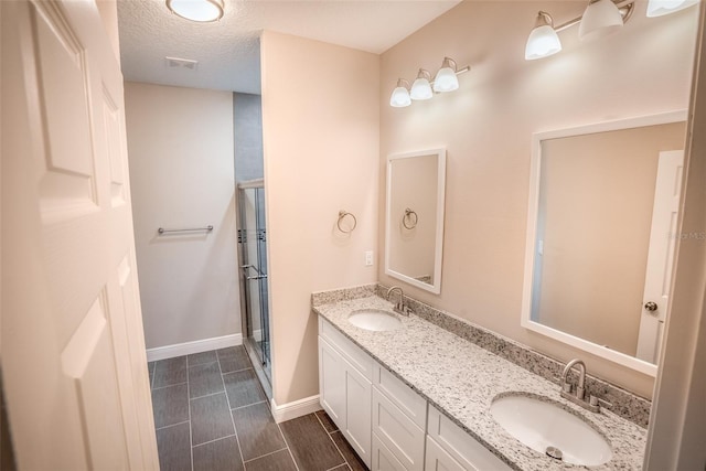 bathroom featuring vanity, a textured ceiling, and an enclosed shower