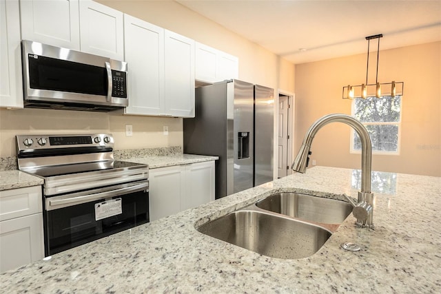 kitchen with light stone countertops, white cabinets, stainless steel appliances, and decorative light fixtures