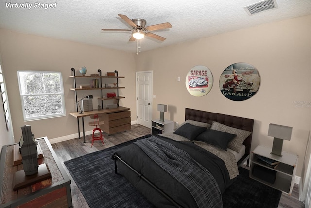 bedroom featuring dark hardwood / wood-style floors, ceiling fan, and a textured ceiling