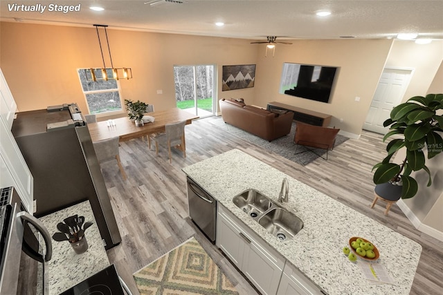 kitchen with pendant lighting, sink, light stone countertops, light wood-type flooring, and white cabinetry