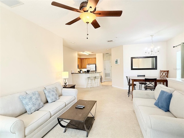 living room with ceiling fan with notable chandelier and light colored carpet