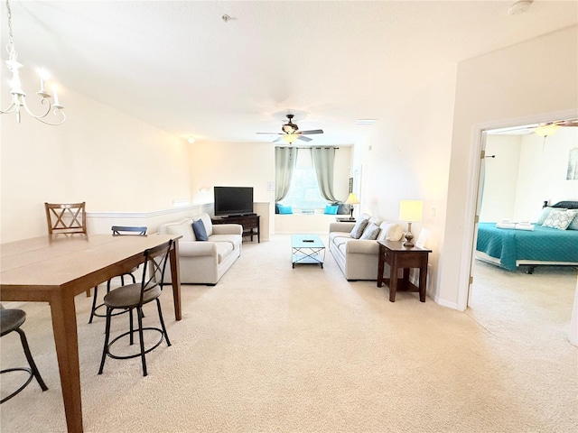 carpeted living room with ceiling fan with notable chandelier