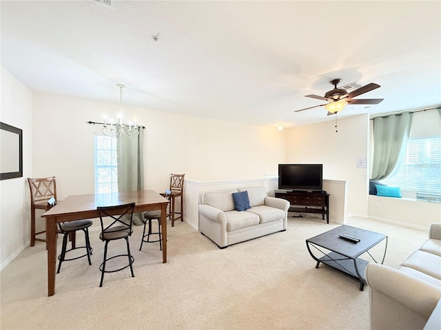 carpeted living room with ceiling fan with notable chandelier