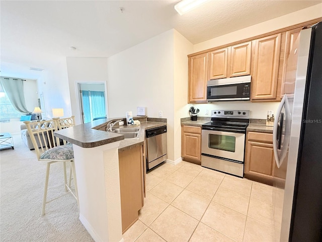 kitchen featuring sink, kitchen peninsula, a breakfast bar area, light tile patterned flooring, and appliances with stainless steel finishes