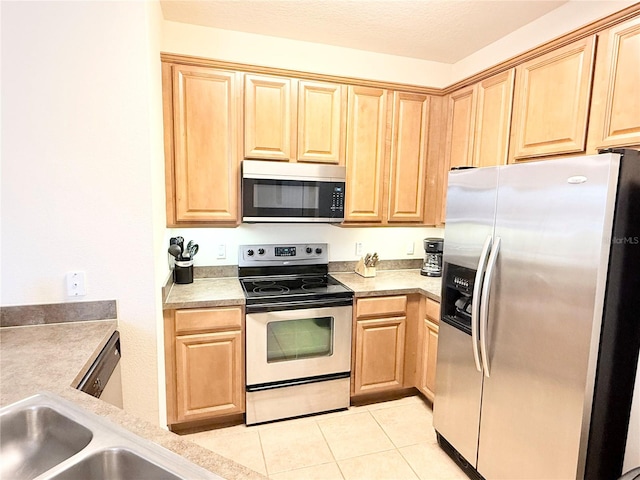 kitchen with appliances with stainless steel finishes, a textured ceiling, light brown cabinetry, and light tile patterned flooring