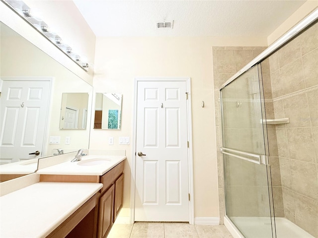 bathroom with tile patterned flooring, vanity, a textured ceiling, and walk in shower