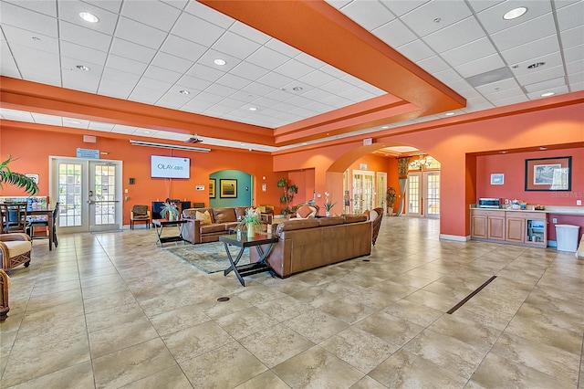 living room with a paneled ceiling, a tray ceiling, beverage cooler, and french doors