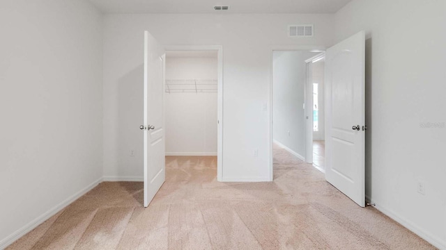 unfurnished bedroom featuring light carpet and a closet