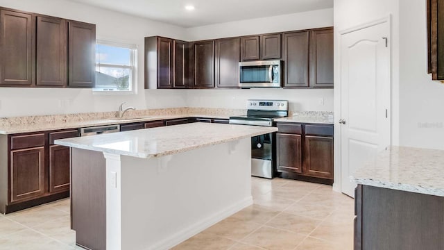 kitchen with dark brown cabinetry, a center island, sink, stainless steel appliances, and light tile patterned floors