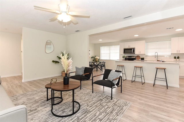 living room with ceiling fan, sink, and light hardwood / wood-style floors