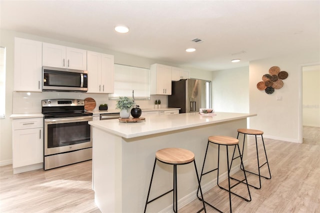 kitchen featuring a center island, white cabinets, light hardwood / wood-style flooring, and appliances with stainless steel finishes