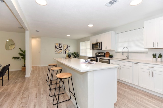 kitchen with white cabinetry, sink, a kitchen island, and appliances with stainless steel finishes