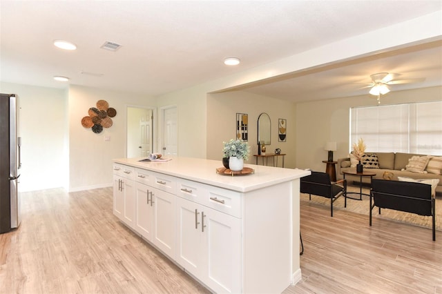 kitchen with ceiling fan, a center island, light wood-type flooring, and white cabinetry