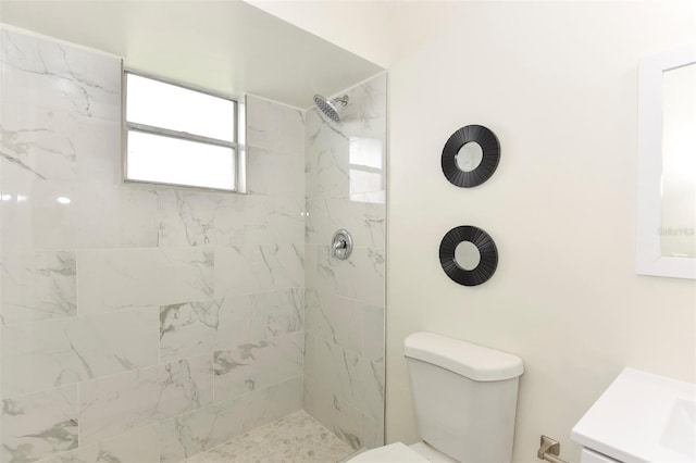 bathroom with a tile shower, vanity, and toilet