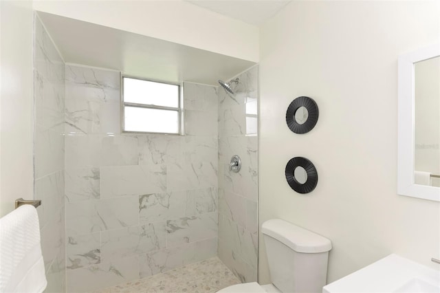 bathroom featuring a tile shower and toilet