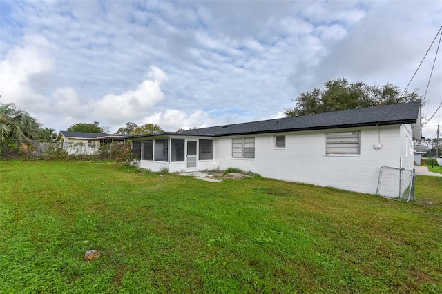 back of house with a sunroom and a lawn