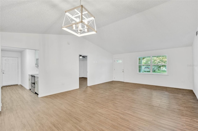 unfurnished living room with a textured ceiling, light hardwood / wood-style flooring, a chandelier, and vaulted ceiling