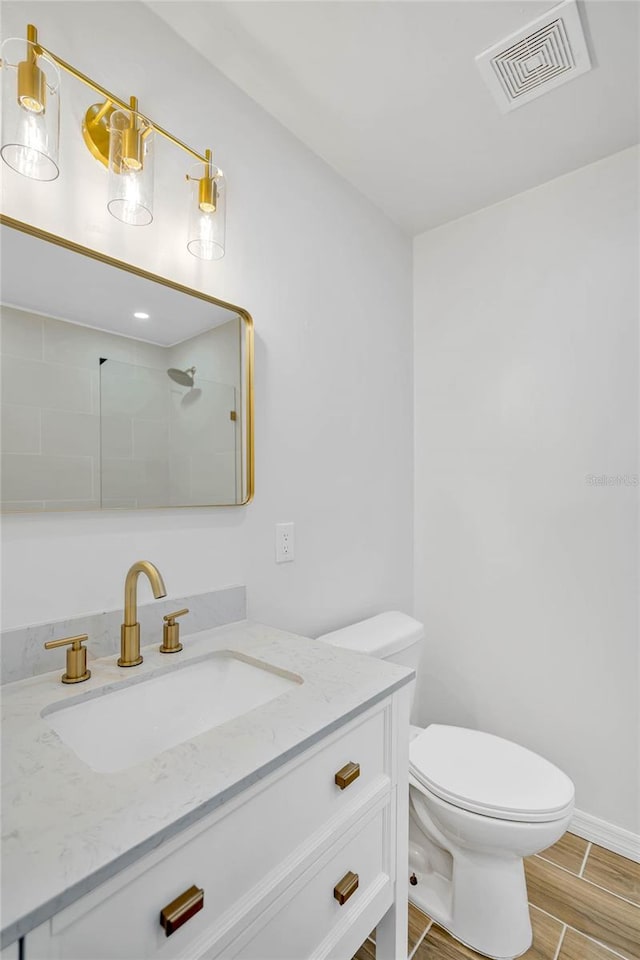 bathroom with hardwood / wood-style floors, vanity, toilet, and walk in shower