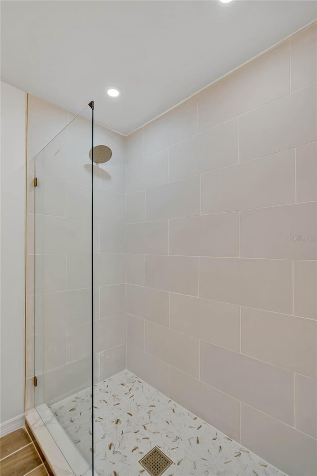 bathroom with tiled shower and wood-type flooring