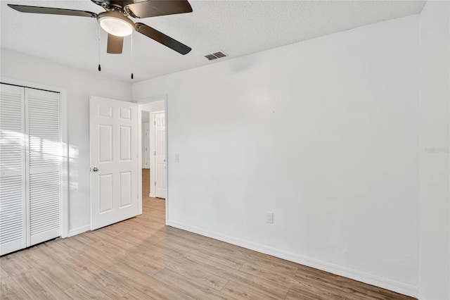 unfurnished bedroom with ceiling fan, light hardwood / wood-style floors, a textured ceiling, and a closet