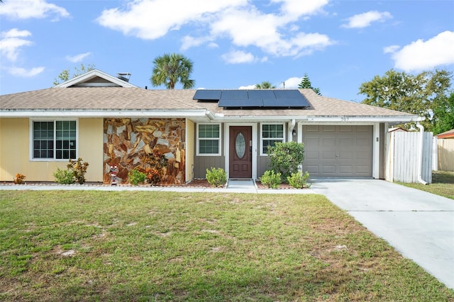 single story home with solar panels, a garage, and a front lawn