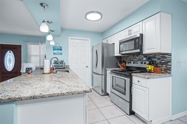 kitchen featuring pendant lighting, decorative backsplash, white cabinetry, and appliances with stainless steel finishes