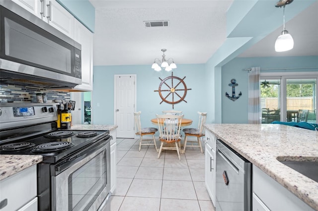 kitchen featuring tasteful backsplash, stainless steel appliances, decorative light fixtures, white cabinetry, and light tile patterned flooring