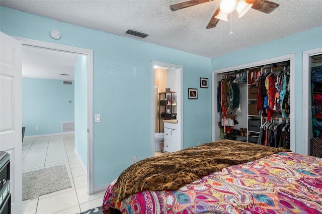 tiled bedroom with ensuite bathroom, ceiling fan, a textured ceiling, and a closet