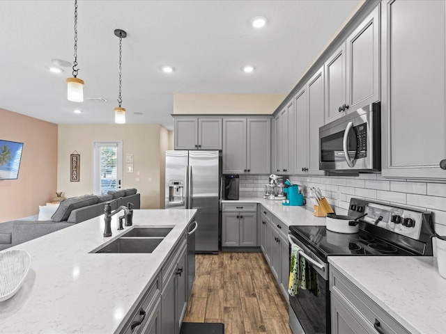 kitchen featuring sink, dark wood-type flooring, decorative light fixtures, gray cabinets, and appliances with stainless steel finishes