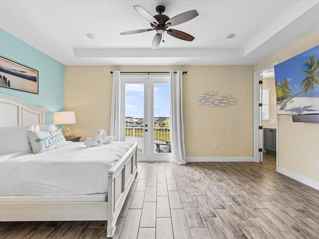 bedroom with ceiling fan, french doors, a raised ceiling, light hardwood / wood-style flooring, and access to outside