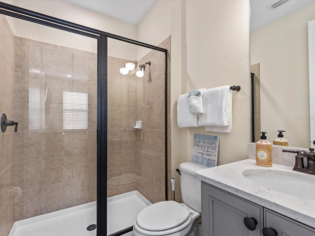 bathroom featuring vanity, toilet, and a shower with door