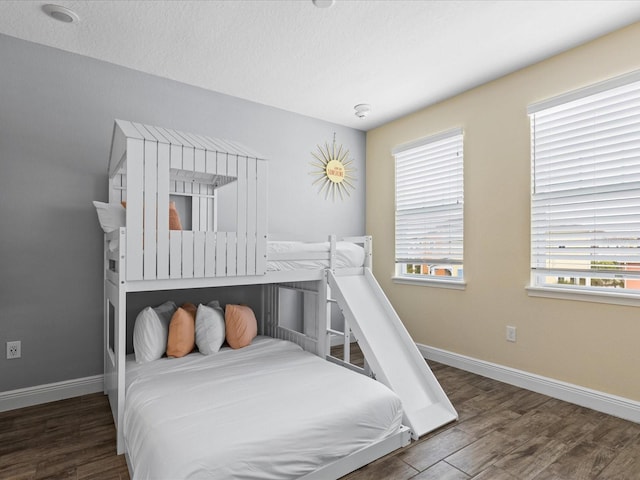 bedroom with a textured ceiling, dark hardwood / wood-style flooring, and multiple windows