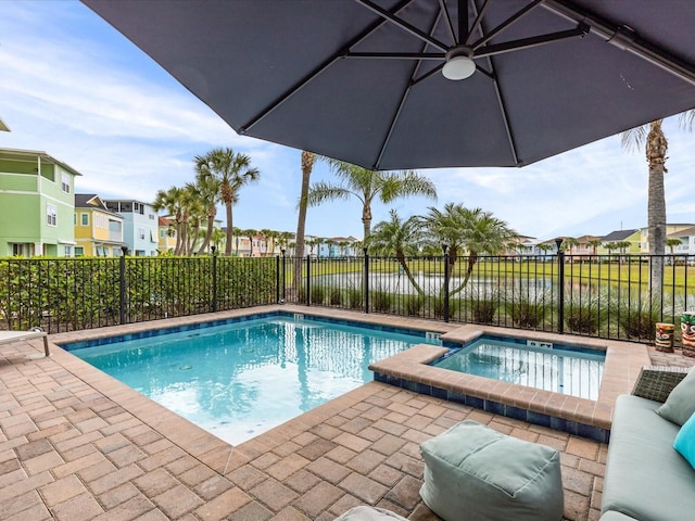 view of swimming pool with an in ground hot tub, a water view, and a patio area