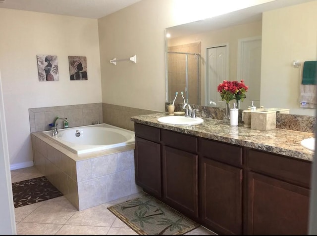 bathroom featuring tile patterned flooring, vanity, and a relaxing tiled tub