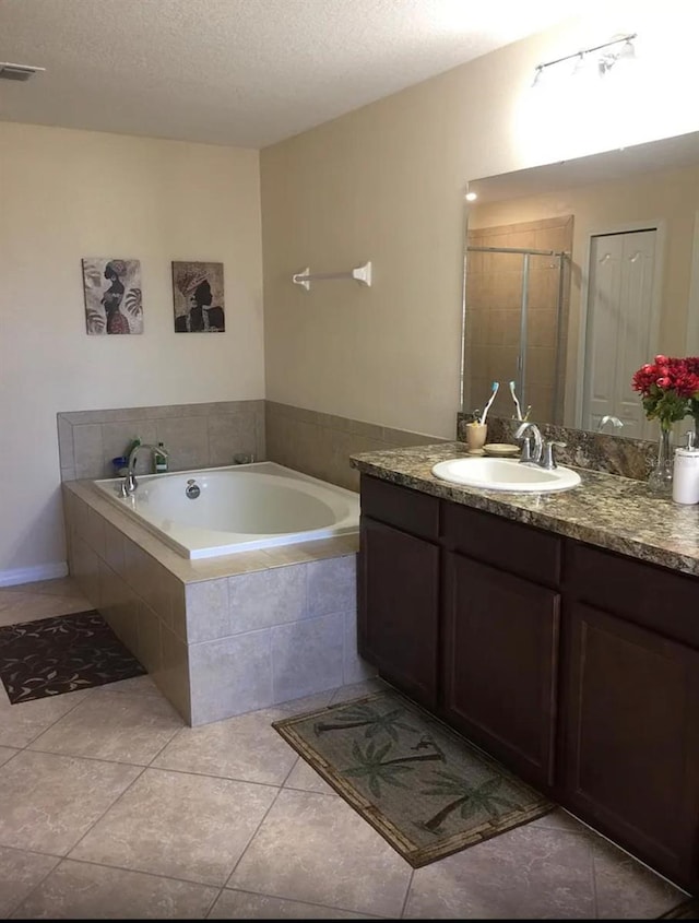 bathroom with tile patterned flooring, vanity, a textured ceiling, and plus walk in shower