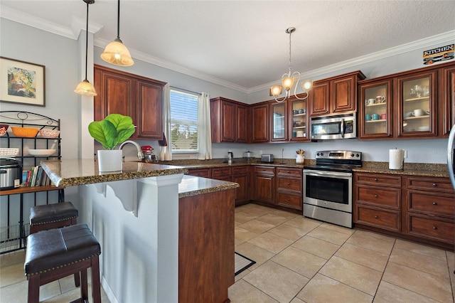 kitchen with dark stone countertops, decorative light fixtures, a kitchen bar, appliances with stainless steel finishes, and ornamental molding