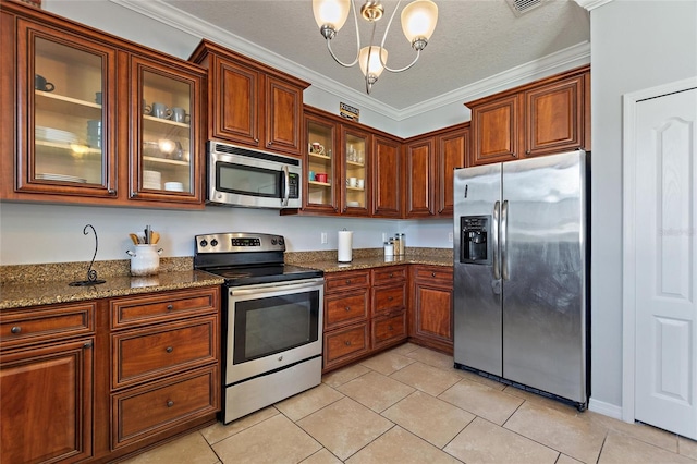 kitchen with dark stone countertops, light tile patterned floors, ornamental molding, a textured ceiling, and appliances with stainless steel finishes