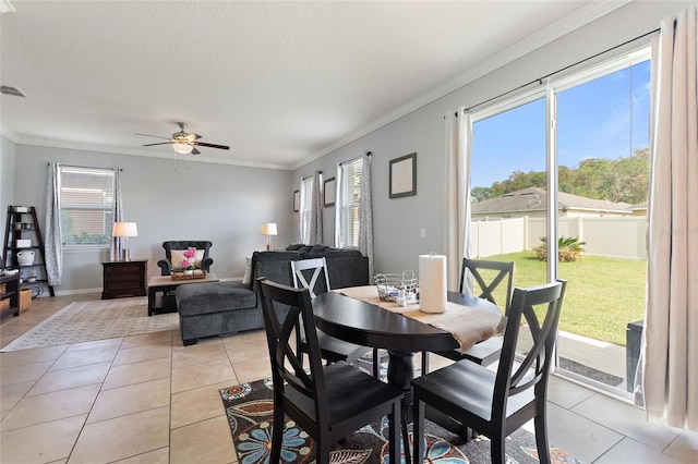 dining area featuring light tile patterned floors, a textured ceiling, ceiling fan, and crown molding