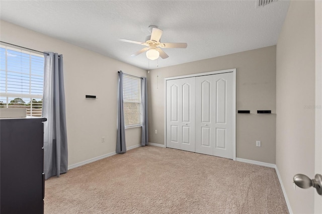 bedroom with ceiling fan, a closet, light colored carpet, and a textured ceiling