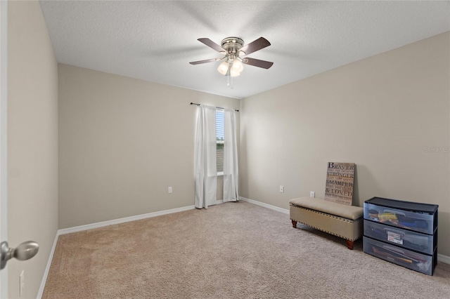 sitting room featuring ceiling fan, light colored carpet, and a textured ceiling