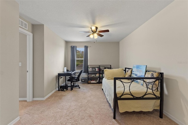 carpeted bedroom featuring ceiling fan and a textured ceiling