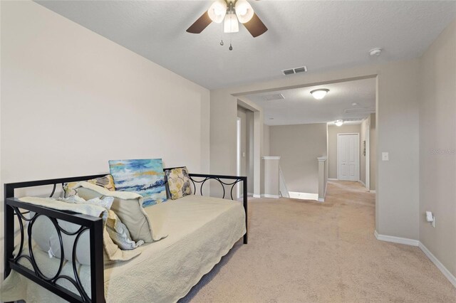 bedroom featuring ceiling fan, light colored carpet, and a textured ceiling