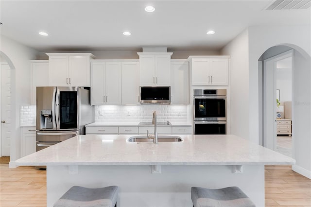 kitchen featuring white cabinets, light hardwood / wood-style flooring, and an island with sink