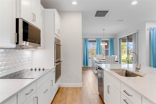 kitchen with sink, stainless steel appliances, light hardwood / wood-style floors, decorative light fixtures, and white cabinets